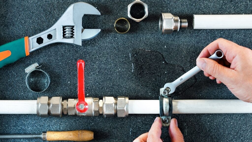 Plumber repairing a pipe valve with an adjustable wrench in Watsonville