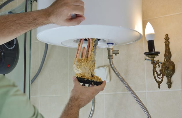 Technician removing mineral buildup from a water heater in Watsonville