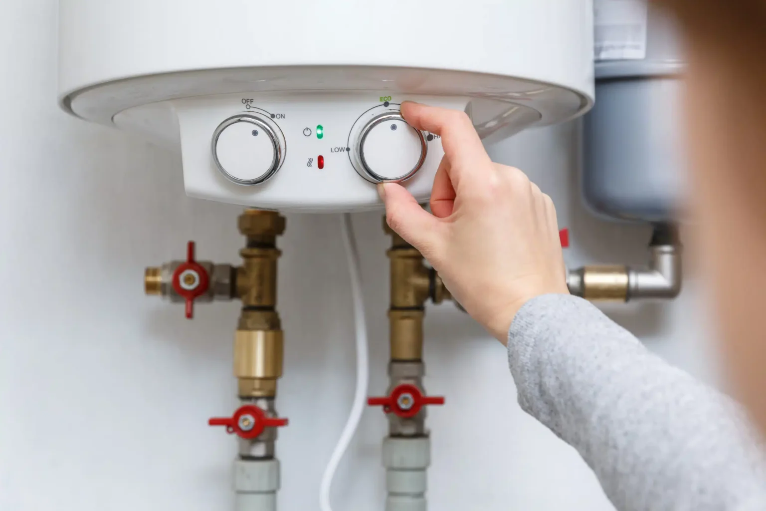 Homeowner adjusting the temperature controls on a water heater in Watsonville